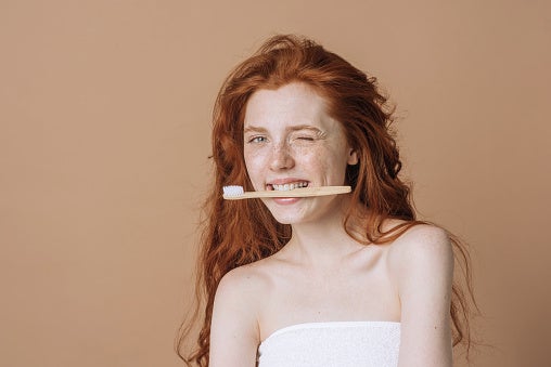 beautiful caucasian woman with tooth eco brush on beige background with copy space.